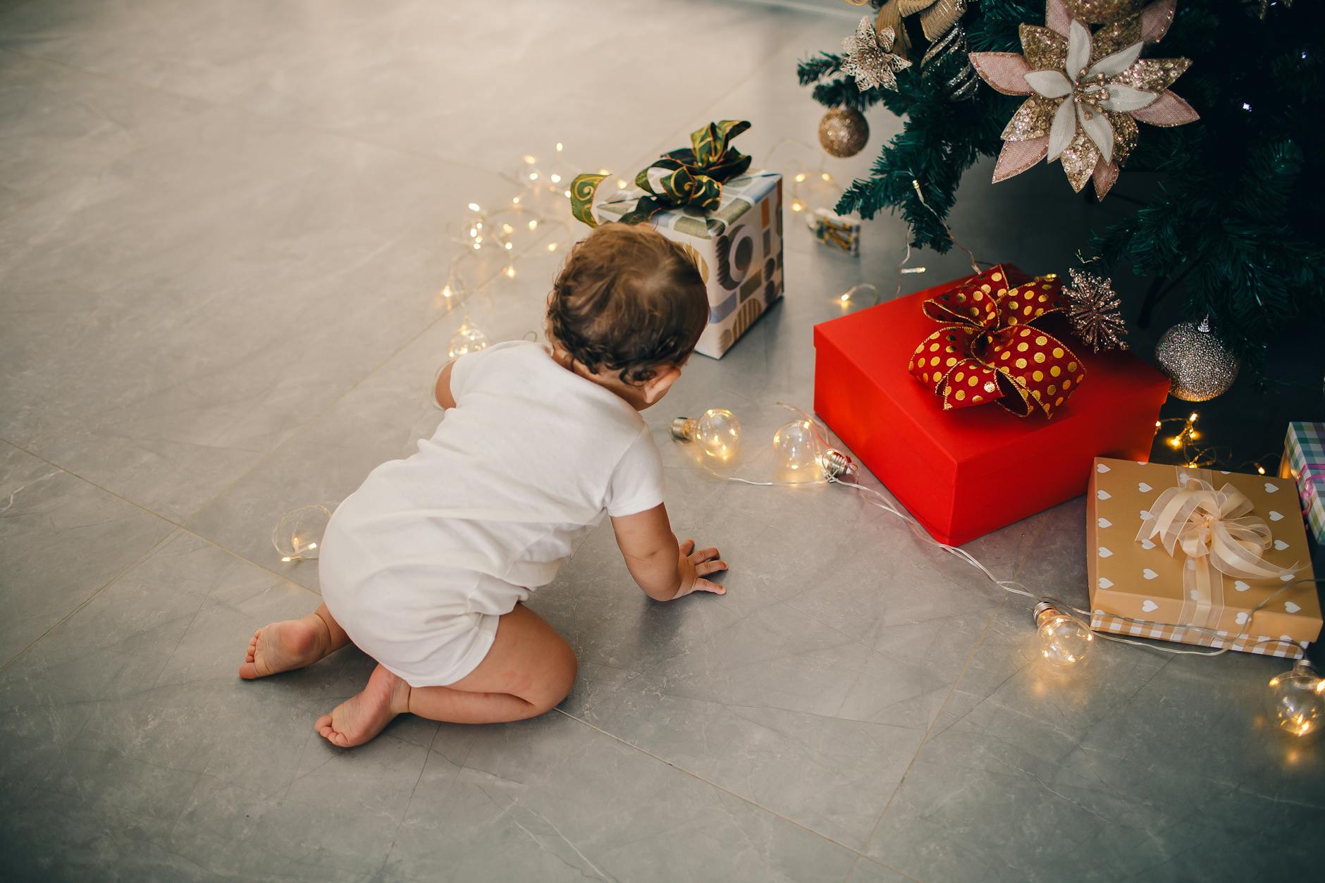 baby crawling on floor under christmas tree