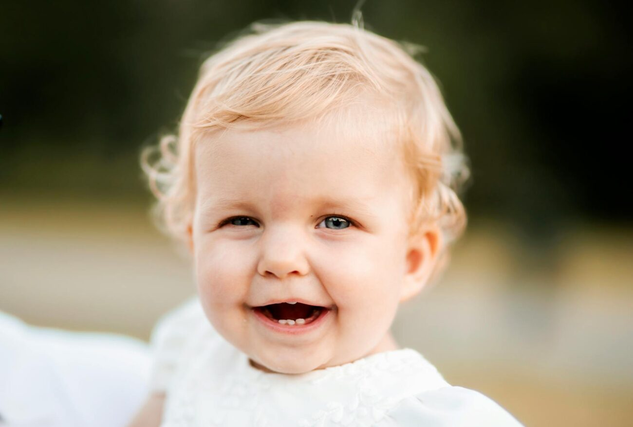 a baby smiling in a white dress