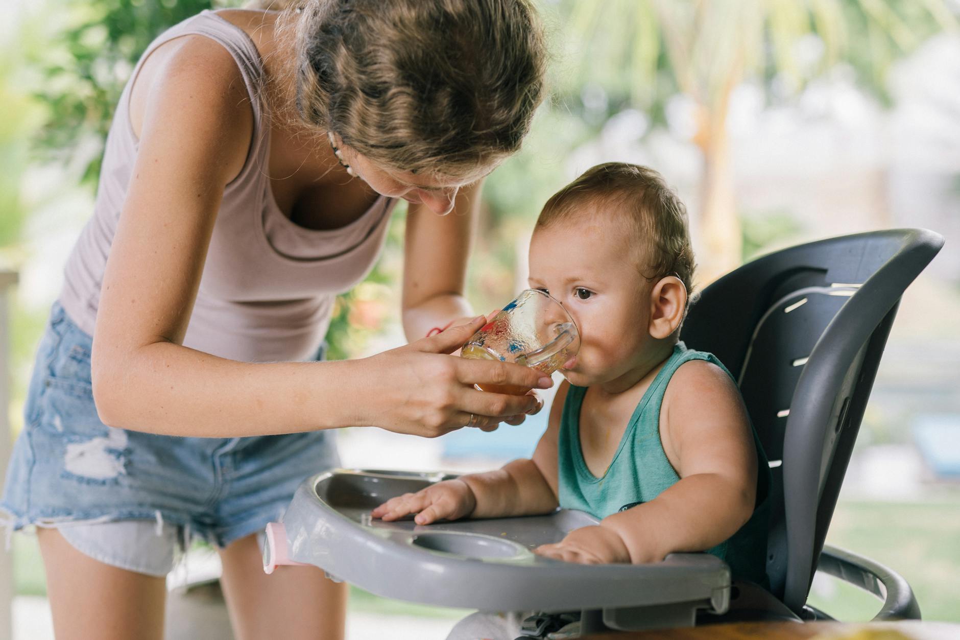 photo of woman assisting baby